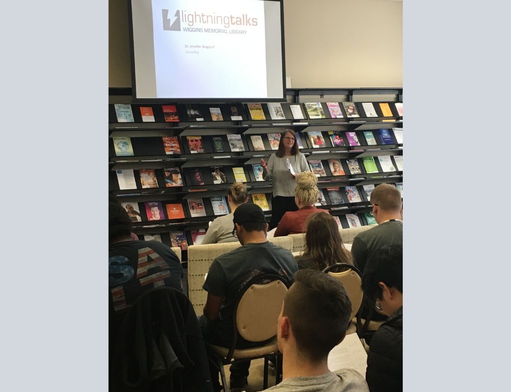 Dr. Jennifer Wagstaff gives a lightning talk to a full audience in the Periodicals Room.