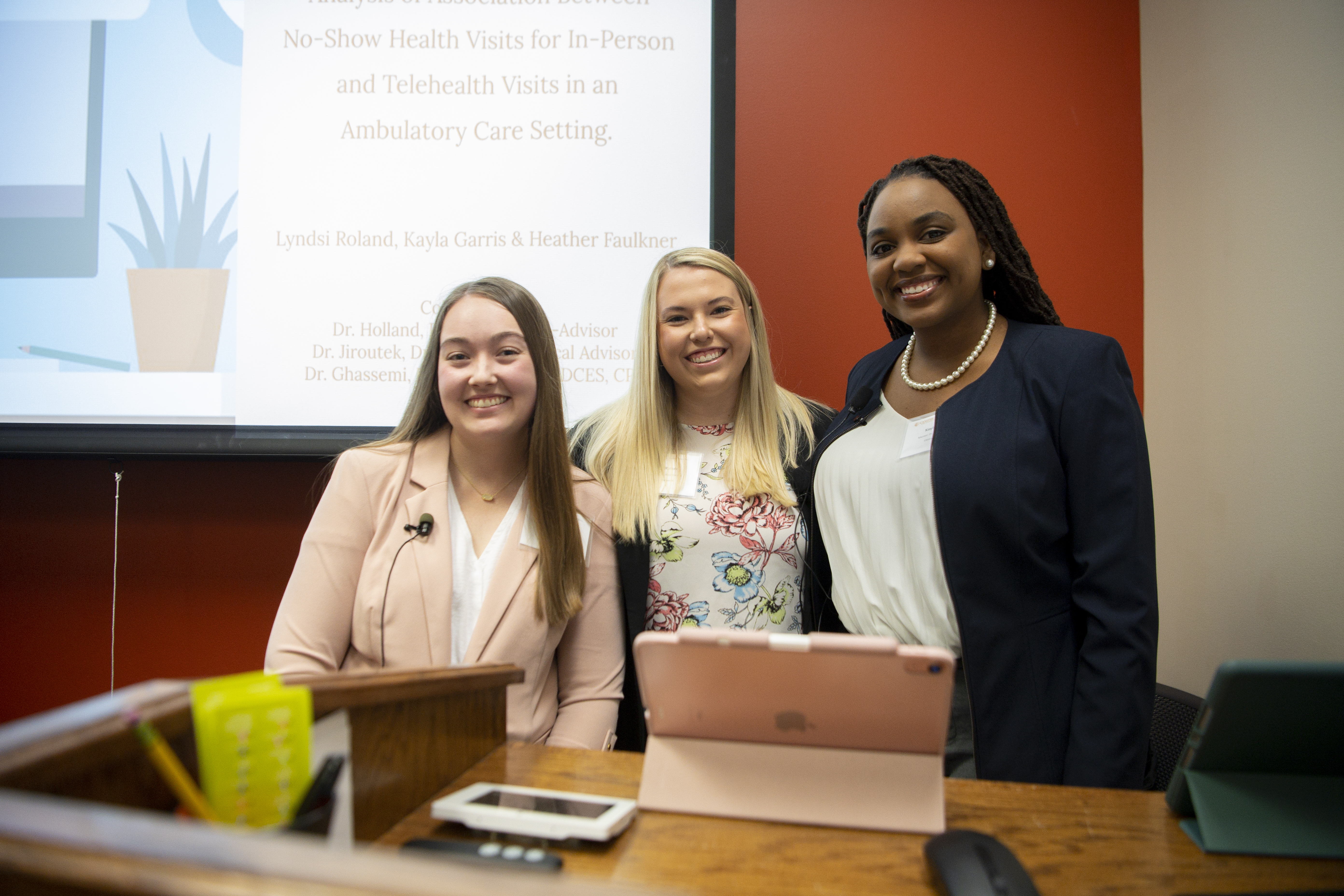 Three Symposium presenters at a podium