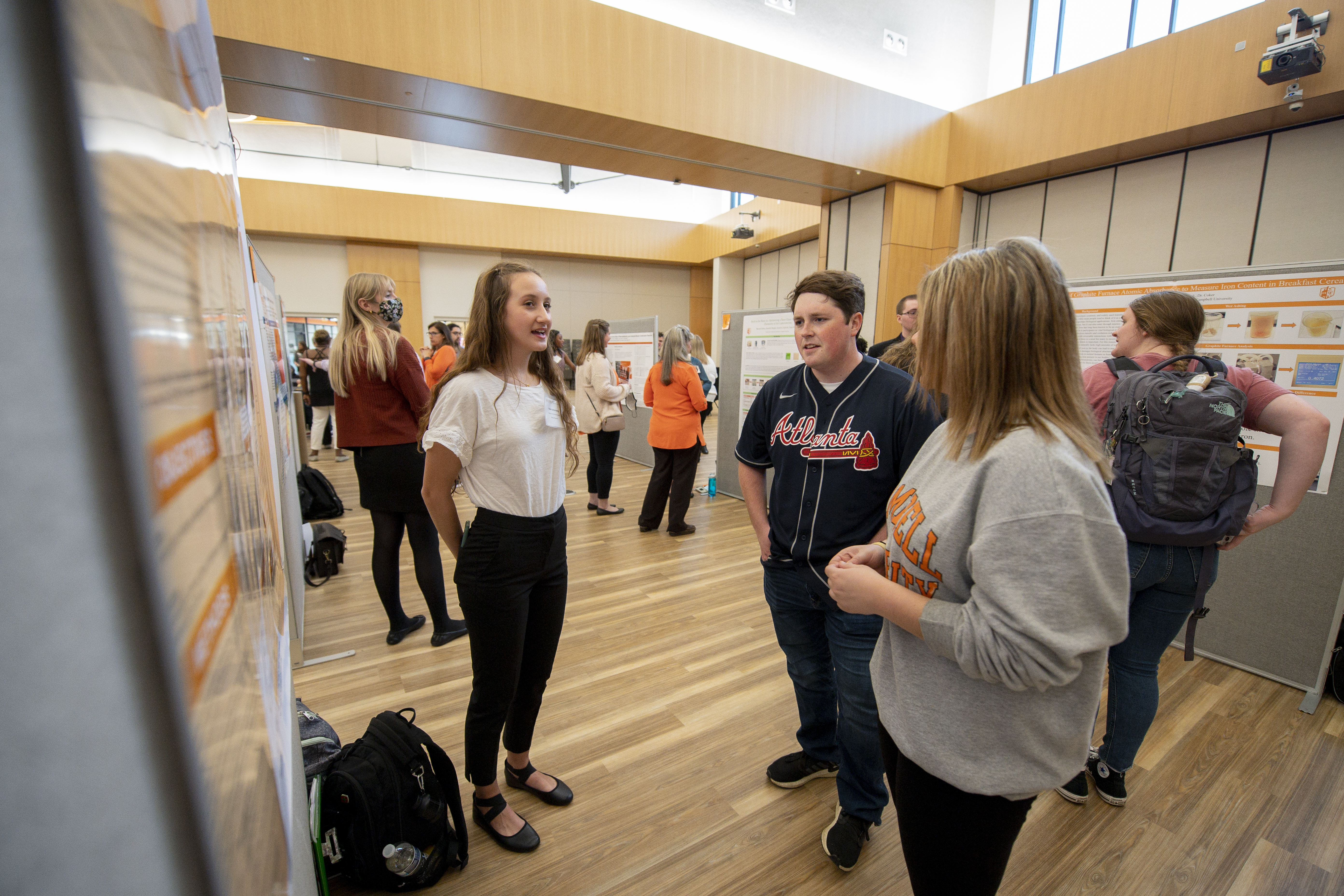 Student discusses her poster with a group of attendees